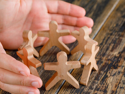 The wooden figures of people holding hands represent solidarity and the collective efforts of human rights activism, civil society organizations, and the pursuit of social justice