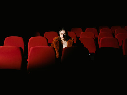 A woman sitting in a movie theater, quietly observing the screen and the surrounding silence