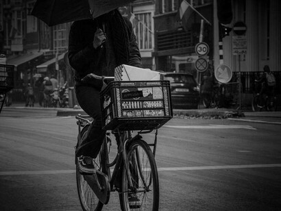 A cyclist covering themselves with an umbrella from the rain in the Netherlands