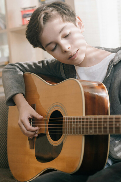 Imagem de um menino talentoso tocando guitarra, trazendo à tona a magia da infância e a conexão com o passado através da música