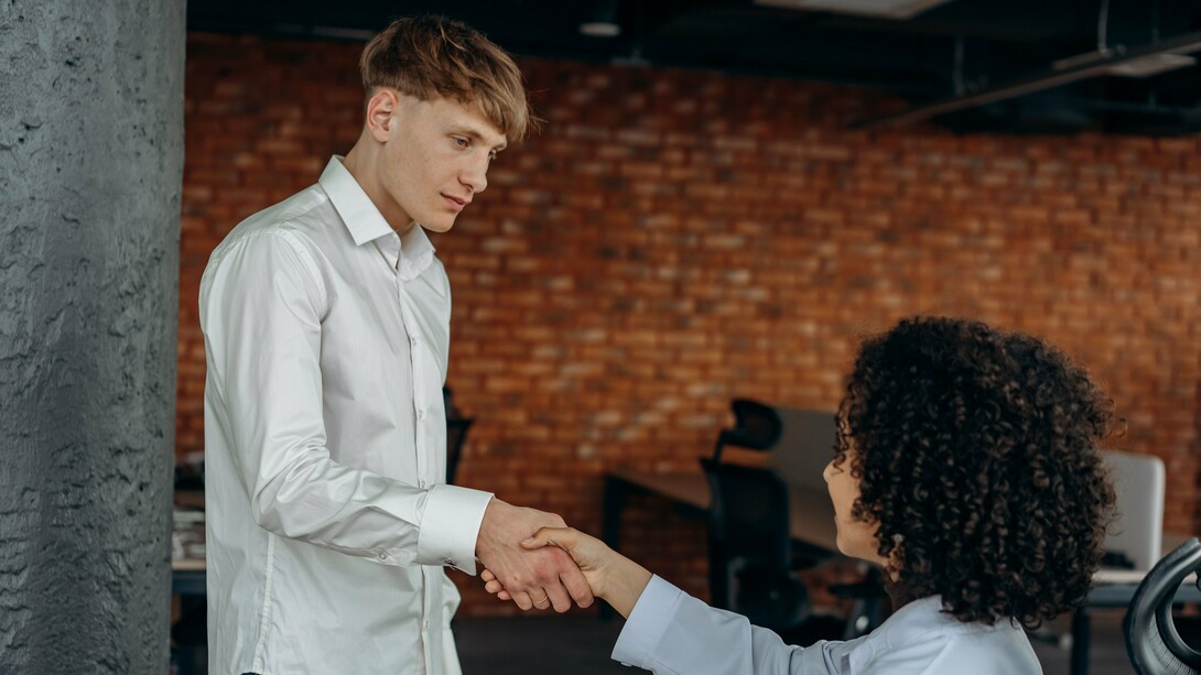 O aperto de mãos estabelece o contato entre duas pessoas, enquanto o semblante contido do homem revela outra dimensão da cena. Nem ausência completa de emoção, nem demonstração intensa de afeto: apenas a neutralidade de quem parece cumprir um gesto social. Quando até a interação humana pode se tornar automática, onde termina a cordialidade e começa a mornidão emocional? Há contato, mas pouca expressão; presença, mas uma distância difícil de nomear