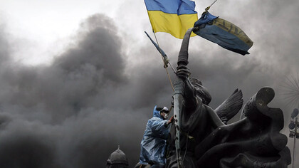 A protester sits on a monument in Kyiv during clashes with riot police