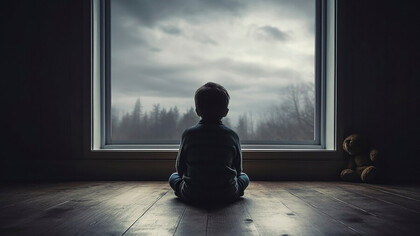 Close-up of a child sitting on the floor in a dark room, struggling with emotional dysregulation