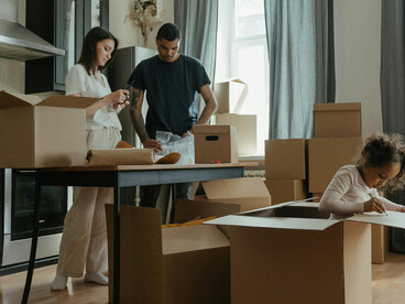 Family settling into their new home, unpacking boxes in a living room filled with moving cartons