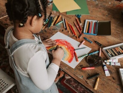Bambina che disegna un arcobaleno, stimolando l'intelligenza creativa