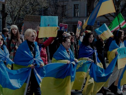 Anti-war protesters march wrapped in Ukrainian flags during a demonstration