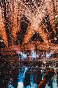 The crowd comes alive under the lights, hands in the air, fully immersed in the energy of the night