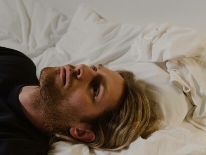 A man slowly coming out of his grief while laying in bed