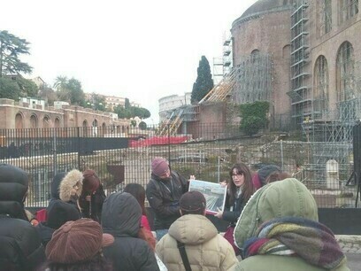 Simona Fanini che spiega la storia dei Fori Imperiali con un diagramma del tempio della Pace con la Basilica di Maxentius alle sue spalle