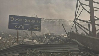 A street sign directing towards Zhytomyr and Kyiv between destroyed buildings, Ukraine