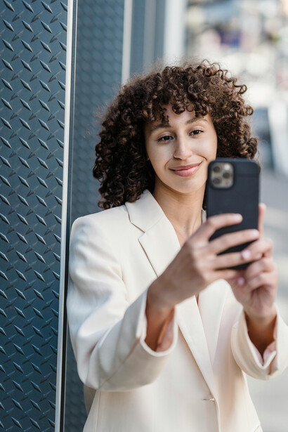Smiling young woman taking a selfie with her smartphone in an urban setting