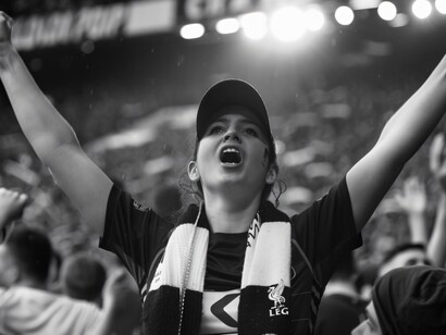 A passionate fan raising her arms in triumph, highlighting the deep emotional connection between supporters and their team