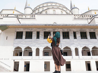 A young woman tourist, elegantly adorned with a hijab, captures the essence of the city as she expertly wields her camera during sightseeing