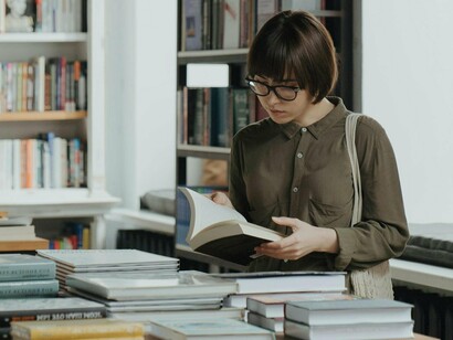 Mulher lê em biblioteca. E os livros de não-ficção? Biografias, autoajuda, história, ciência... A lista é longa! Esses livros são excelentes para aprender coisas novas, entender o mundo ao nosso redor e até descobrir novas paixões e interesses. Não-ficção pode ser tão fascinante quanto qualquer romance, dependendo do seu interesse e curiosidade
