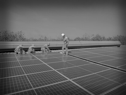 A solar energy crew installing solar panels on the roof of a commercial building