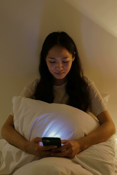 A woman in a brown tank top poses confidently in front of a smartphone camera, reflecting the curated image of a social media influencer
