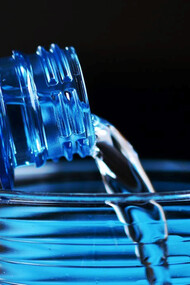 Clear glass and a water bottle with a mesmerizing visual as water gracefully flows from the bottle into the waiting glass