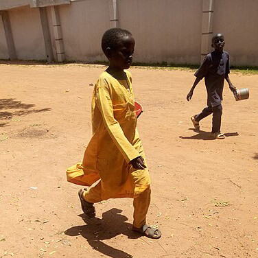 An Almajiri girl walks peacefully in Nigeria, contrasting with the struggles many children in the system face