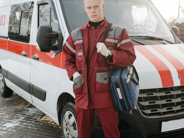 Emergency responder standing ready beside an ambulance, representing the frontline preparedness needed to protect vulnerable communities during El Niño-driven disasters