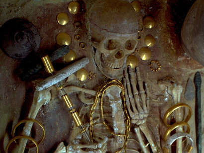 The Varna Necropolis, discovered in 1976 and dated to the 5th millennium BCE, includes graves containing the oldest known worked gold in human history. One of the most significant burials is that of a man estimated to be around 35 years old, often interpreted as a ruler or elite figure. He was buried with a golden scepter, large gold armbands, gold buttons from a cloak, as well as copper and stone axes