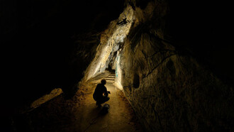 Hombre observa un pasadizo dentro de una de las Cuevas de Cantabria, España 