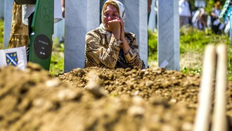 Una mujer llora ante una tumba en el memorial y cementerio de Srebrenica