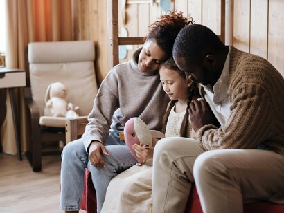 O casal acaricia a filha enquanto ela brinca tranquilamente entre os dois. O texto defende que o diálogo, o respeito e a presença da família continuam fundamentais para a construção de lares harmoniosos
