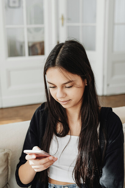 A woman dressed in black long sleeves watches short drama episodes on her mobile phone, reflecting the binge-worthy appeal of vertical serie