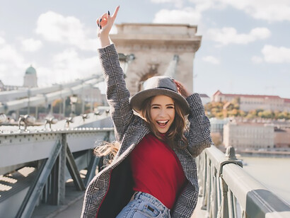 A stylish solo female traveler, dressed casually, enjoys exploring the vibrant cityscape, radiating joy and a sense of adventure