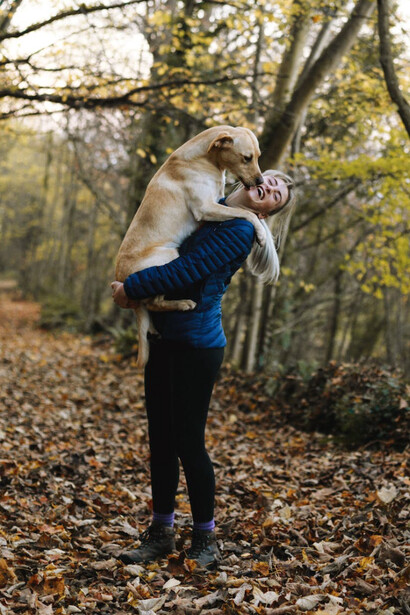 Donna in un bosco che si gode l'aria aperta e la compagnia del proprio cane: passeggiare ed esplorare nuovi luoghi fa bene alla mente e diminuisce lo stress