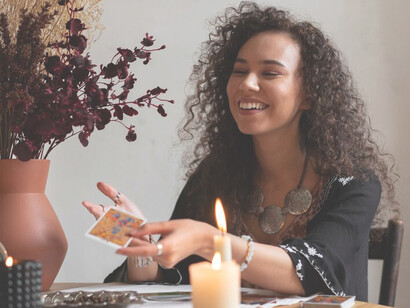 A woman sitting at a table, reading Oracle cards