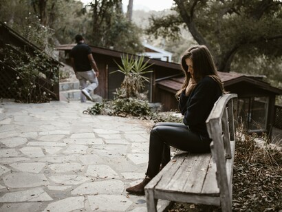 A man walking away from a woman sat on a bench