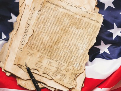 The Declaration of Independence displayed against the Stars and Stripes, symbolizing the ideals of liberty and equality that shaped America