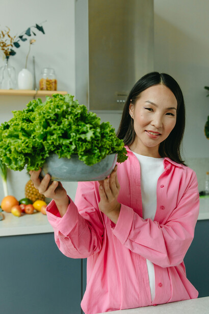 A woman carrying a bowl of fresh lettuce, representing a plant-based diet, vegan lifestyle, and healthy eating