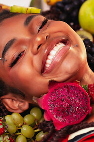 A smiling girl surrounded by colorful Brazilian fruits
