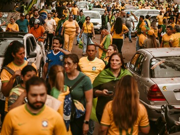 Manifestantes ocupam a via pública, enquanto carros aparecem no cenário da mobilização. Nas redes sociais e nas ruas, a repetição de mensagens pode alimentar certezas e intensificar a polarização, tornando cada vez mais difícil distinguir informação, manipulação e discurso de ódio