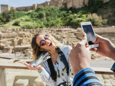 A man photographing his girlfriend in front of a monument