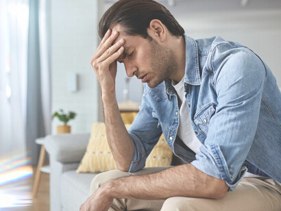 Overwhelmed by anxiety and stress, a young man sits alone at home, struggling with his feelings of depression