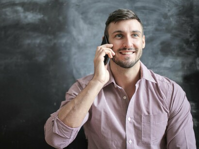 A man on the phone with customer support starts the call with a smile, hopeful that they will quickly resolve the issue