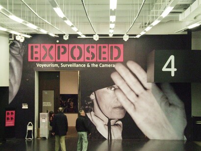 Exposição 'Exposed: Voyeurism, Surveillance and the Camera', em Londres, Inglaterra. Nos Estados Unidos e na Europa, diversos artistas têm explorado o papel da vigilância como mecanismo de controle social e disciplinar. Hasan Elahi, por exemplo, converteu sua experiência pessoal de ser um suspeito do FBI em um projeto de autovigilância radical