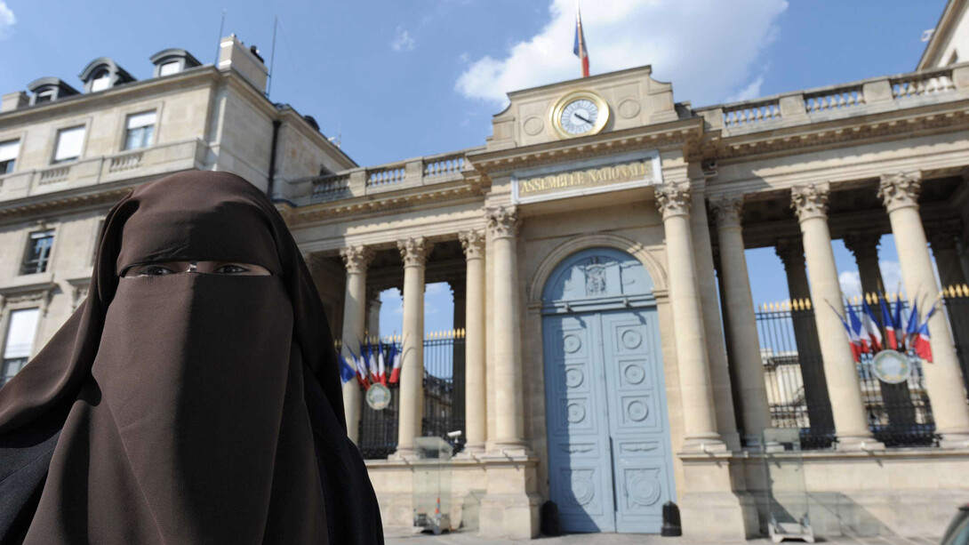 Mujer musulmana con nicab delante de la Asamblea Nacional de Francia, órgano legislativo que prohibió su uso en espacios públicos en 2010