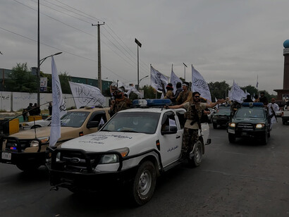 Taliban fighters travel in a captured Humvee following the Fall of Kabul in August 2021