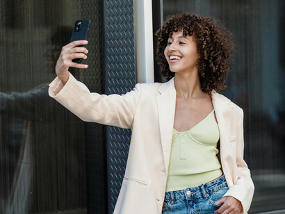 Smiling woman using her smartphone to take a selfie outdoors in the city