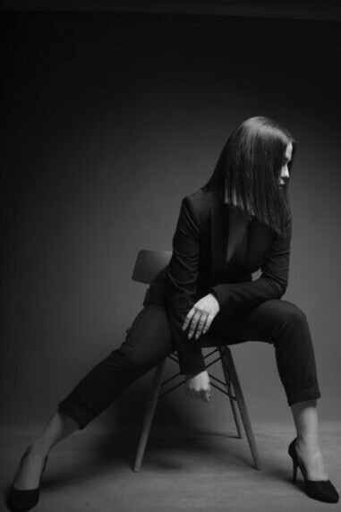 A woman seated in a chair, wearing a suit