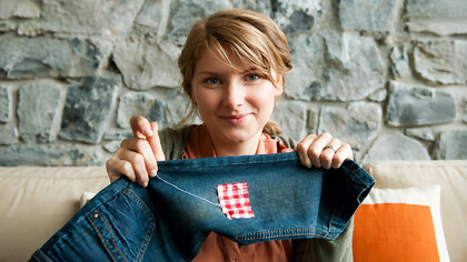 Woman repairing a pair of jeans using traditional visible mending techniques