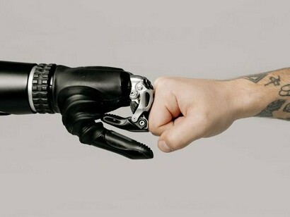 A human fist bumping hands with a robotic hand, representing the trusted partnership between people and autonomous AI