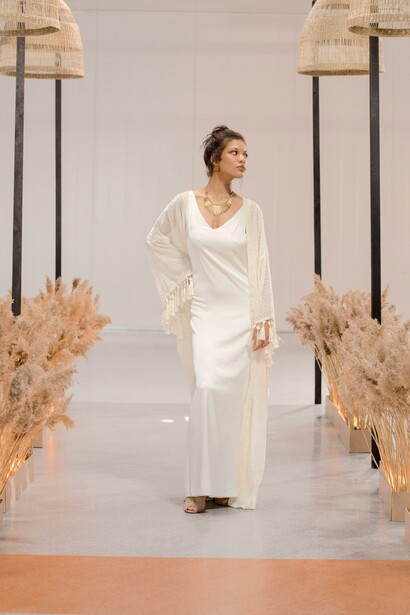 Uma modelo usando um vestido branco andando na passarela