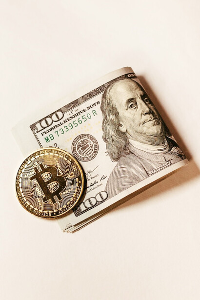 A bitcoin sitting on top of a pile of money