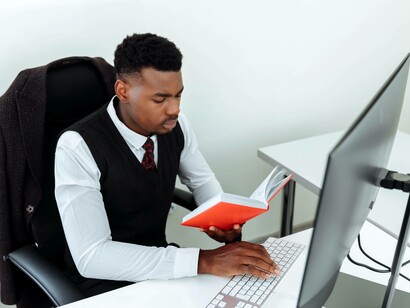 A business school student typing notes on his computer