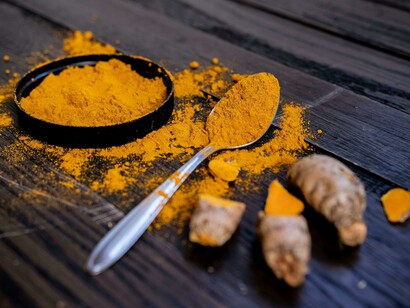 Close-up of ground turmeric alongside fresh turmeric root